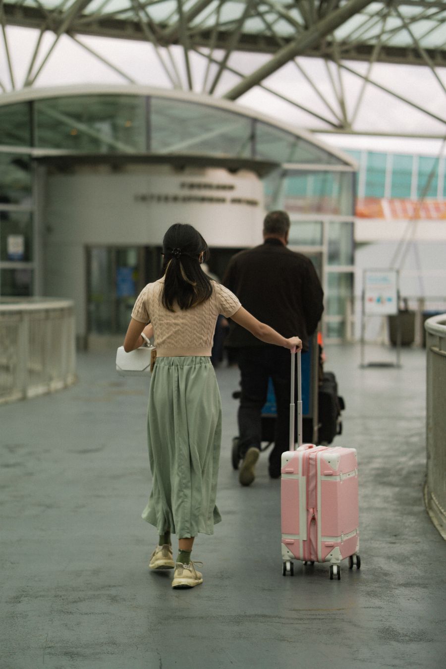 woman in brown t shirt pushing her pink luggage and man in black long sleeves pushing trolley — Noches en Nicaragua: planes de cena, traslados y reseñas, todo al instante.