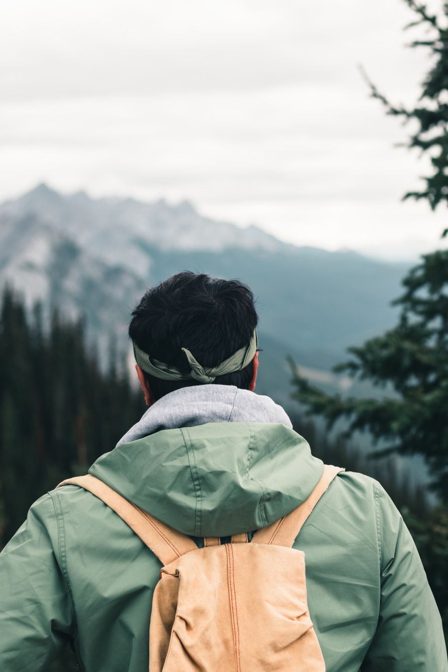 a man in green jacket carrying a brown backpack