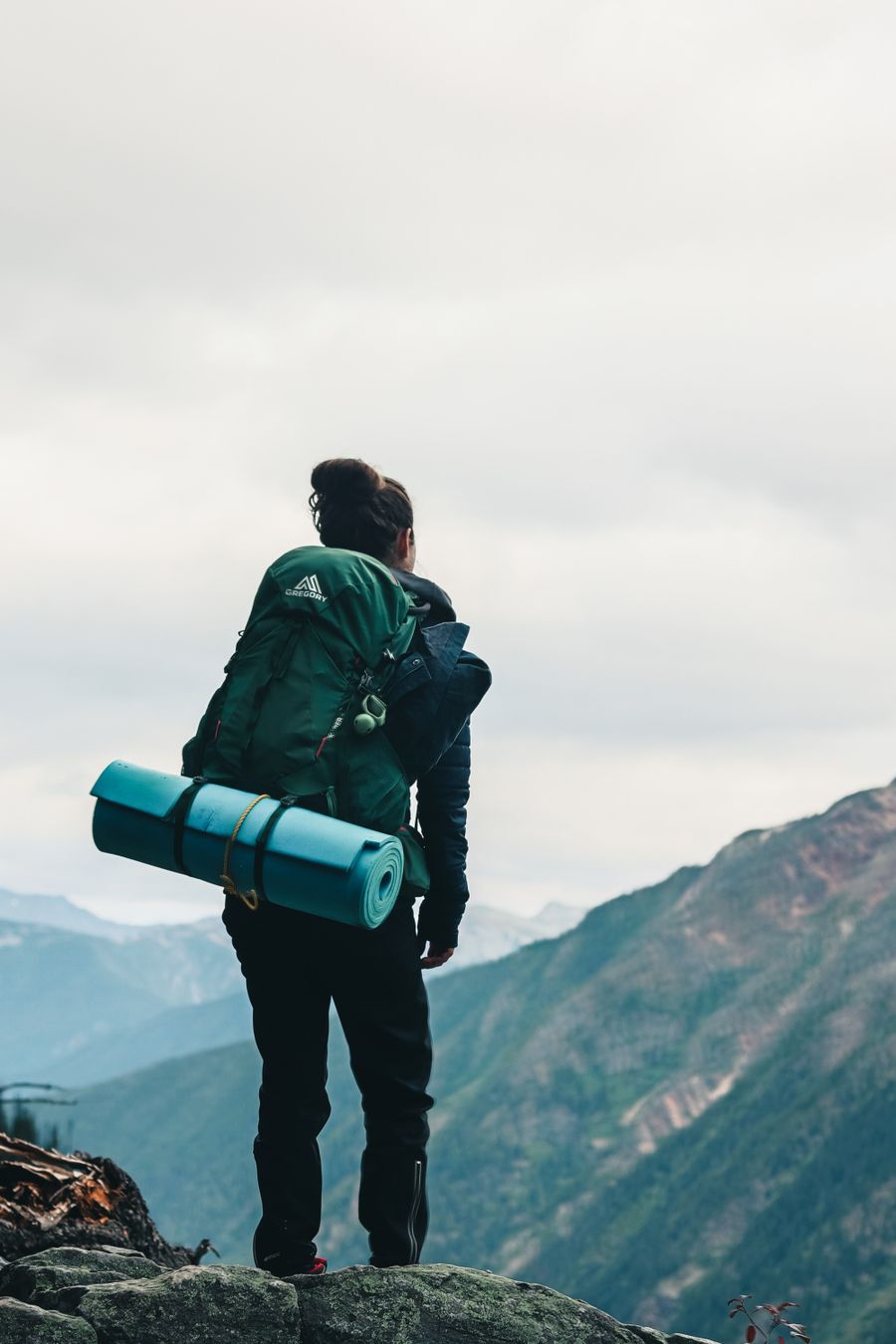 a backpacker looking at the scenery while standing on the edge of a mountain