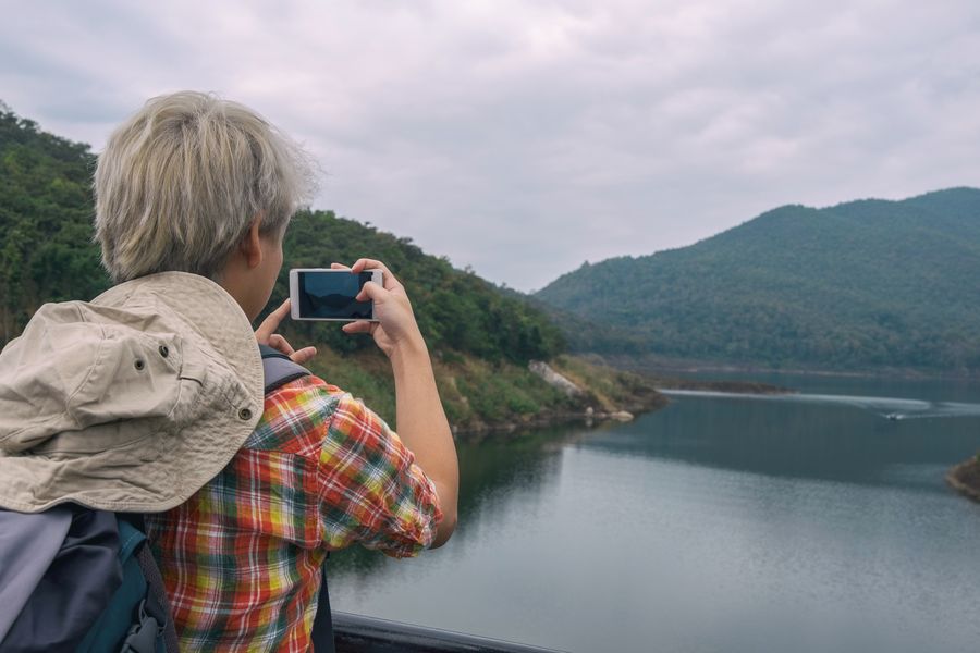 Person photographing a beautiful mountain lake view with a smartphone, enjoying outdoor adventure. — Support: A nivel de calle: navegación, traslados y reseñas, todo al instante.