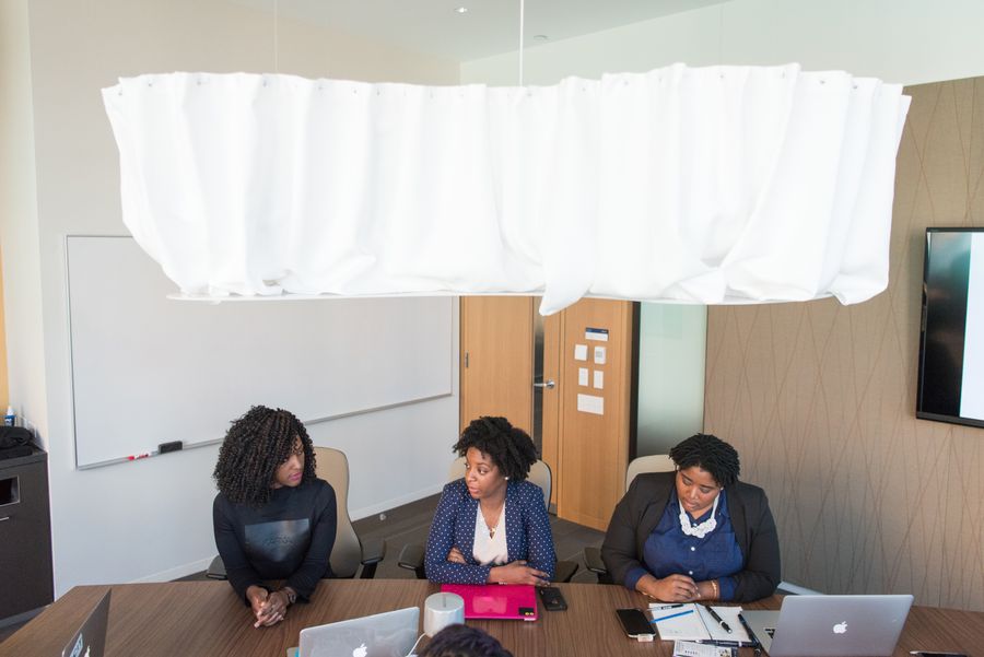 three women wearing formal clothes sitting in front of conference table — The modern arrival: online before the seatbelt sign goes off.
