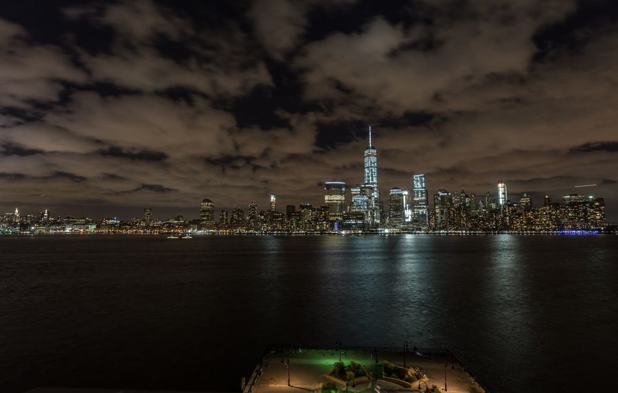 new york cityscape behind sea at night — Docs: Los docs asumen que estás en un aeropuerto — cortos, escaneables, correctos.