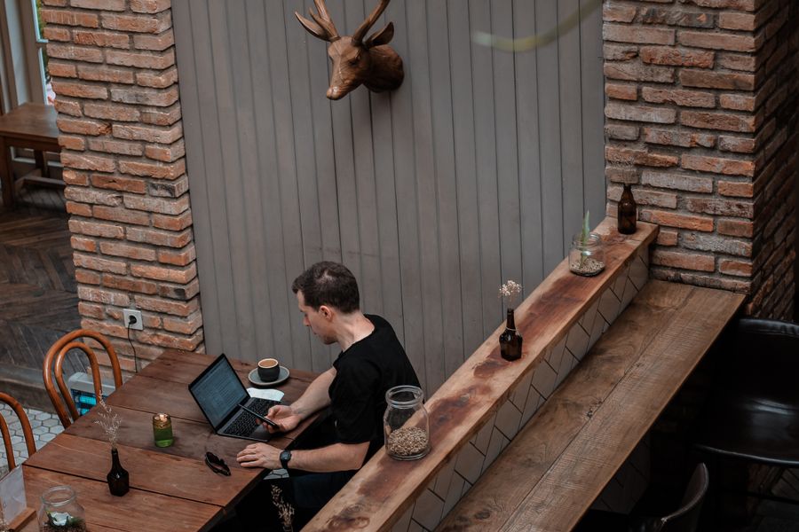 man sitting in front of his laptop white looking at his phone