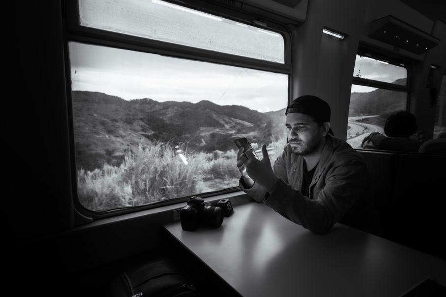 Man using a smartphone on a train journey through scenic landscape. — Amanecer sobre Paraguay: clima revisado, botas puestas, datos activados.