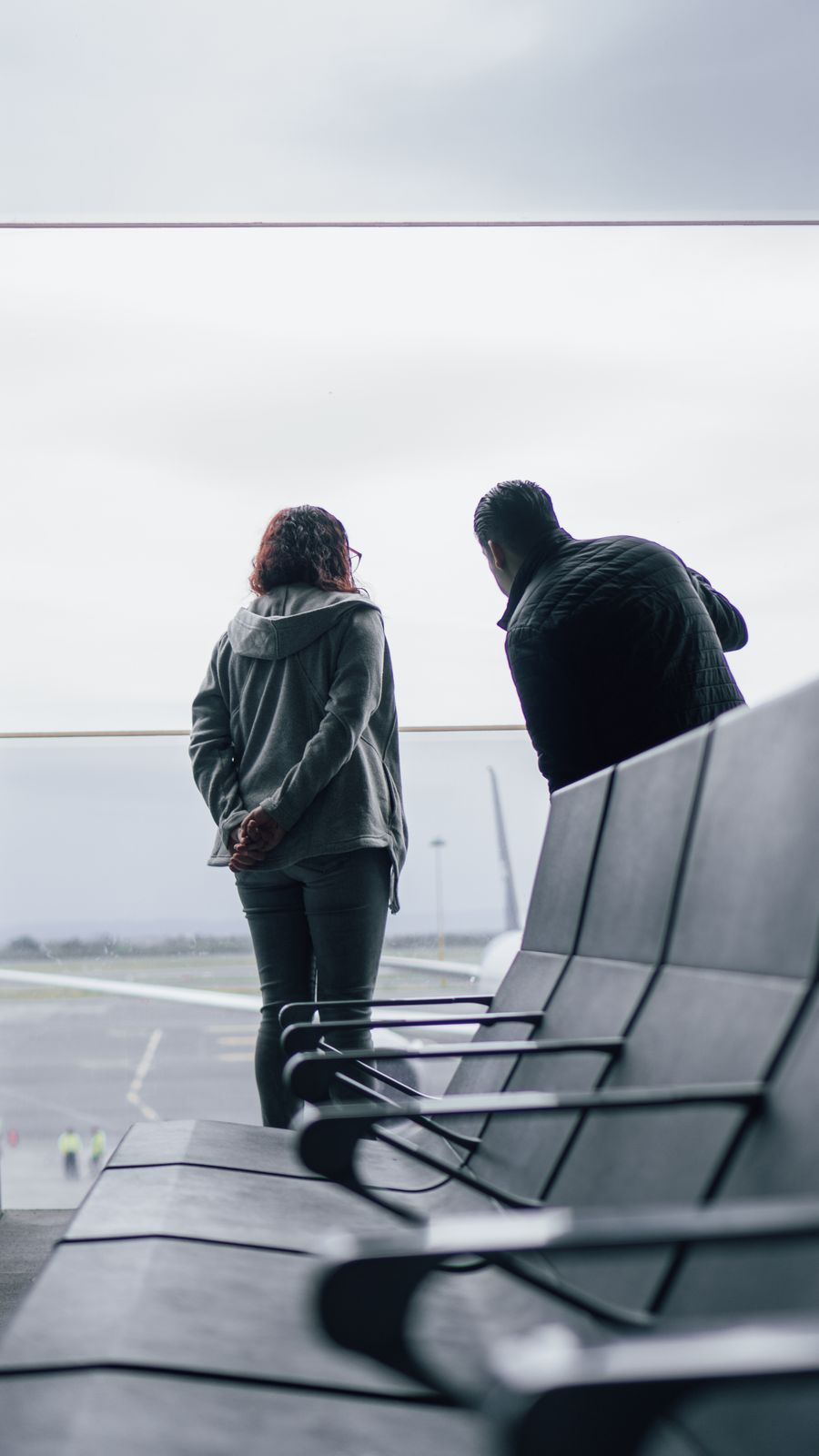woman and man standing near windows on airport — Día de salida en Uruguay: salida tardía solicitada, taxi sincronizado con el vuelo.