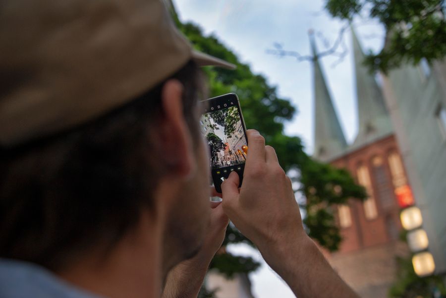 A person captures iconic Berlin church towers using a smartphone, outdoors. — Los chats grupales siguen vivos en cada frontera alrededor de Nicaragua.