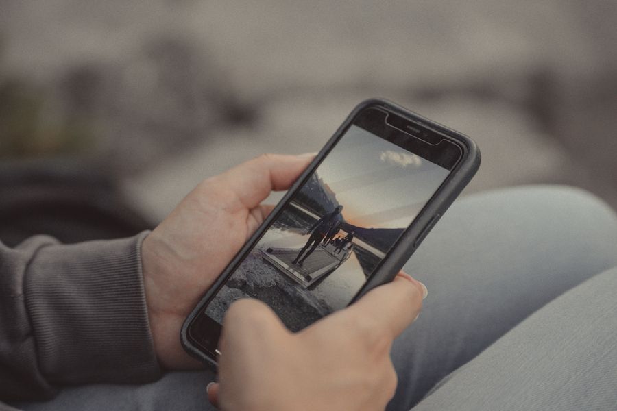 Close-up of hands holding a smartphone showing a mountain scene, captured outdoors in Banff. — Día de mercado en Argentina: búscalo, tradúcelo, paga con el teléfono.