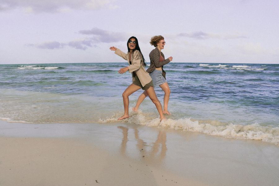 smiling women running on sea shore — Las filas de check-in avanzan más rápido cuando tus documentos están en el teléfono.