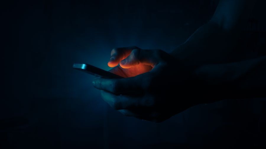 man holding a mobile phone in the dark — Data Usage Estimator accepts your trip details and hands back a clear recommendation.