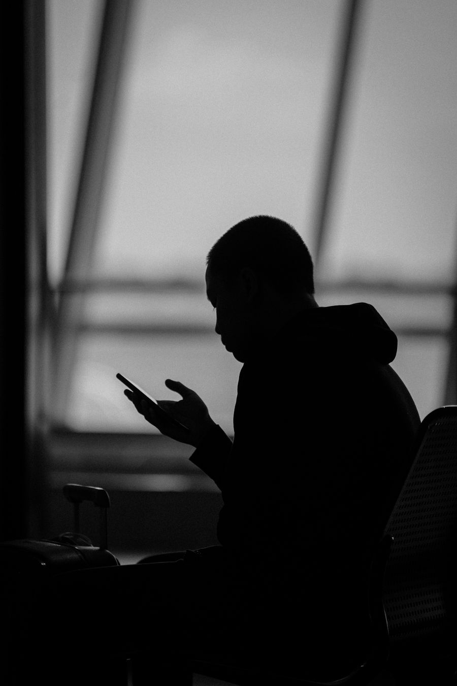 Silhouette of a man using a smartphone in an airport terminal in Surabaya, Indonesia. — Resend eSIM QR Code remembers, so repeat travelers barely type.