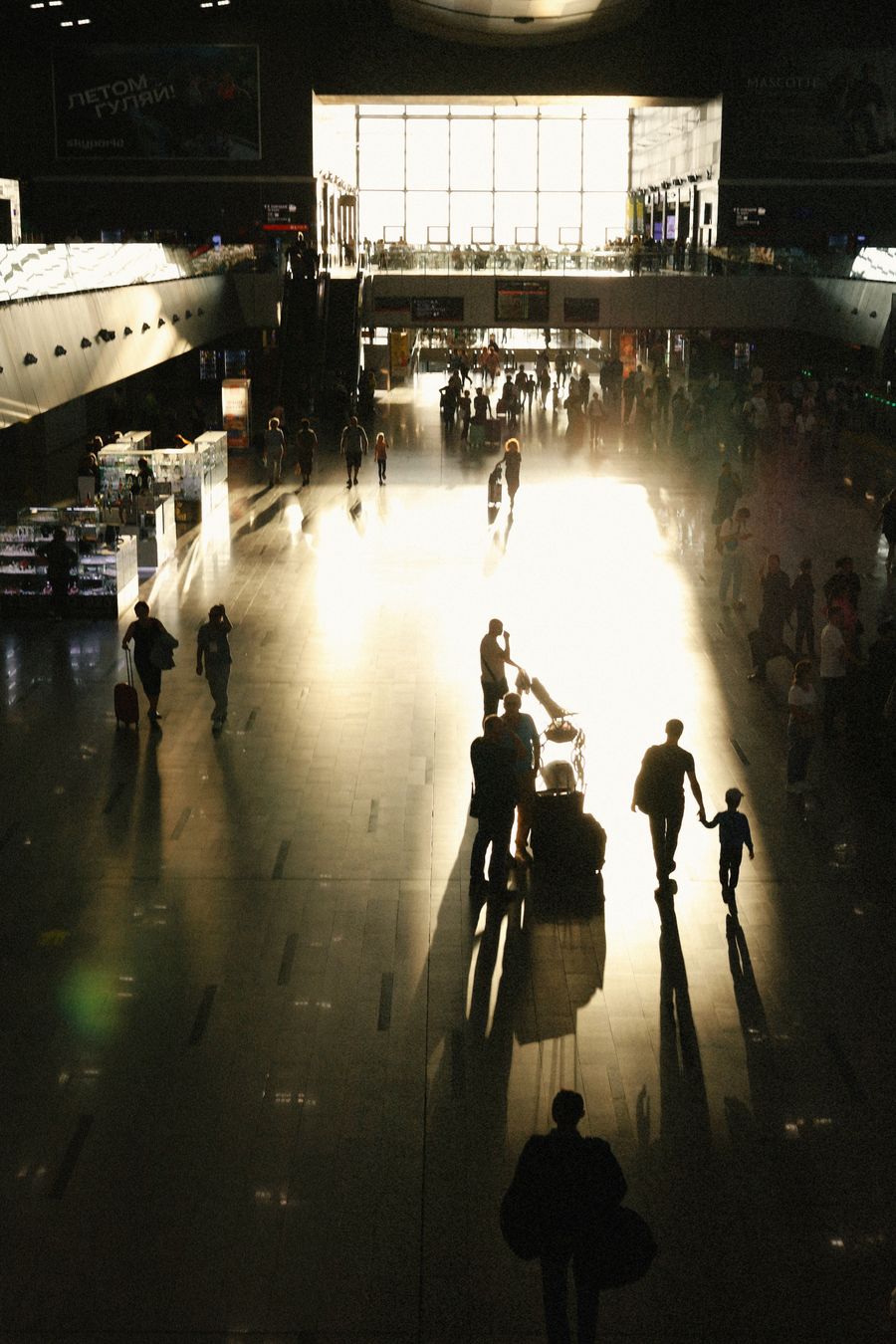 busy airport terminal with silhouetted travelers — Caza de souvenirs en Costa Rica con conversión de moneda en vivo en el bolsillo.