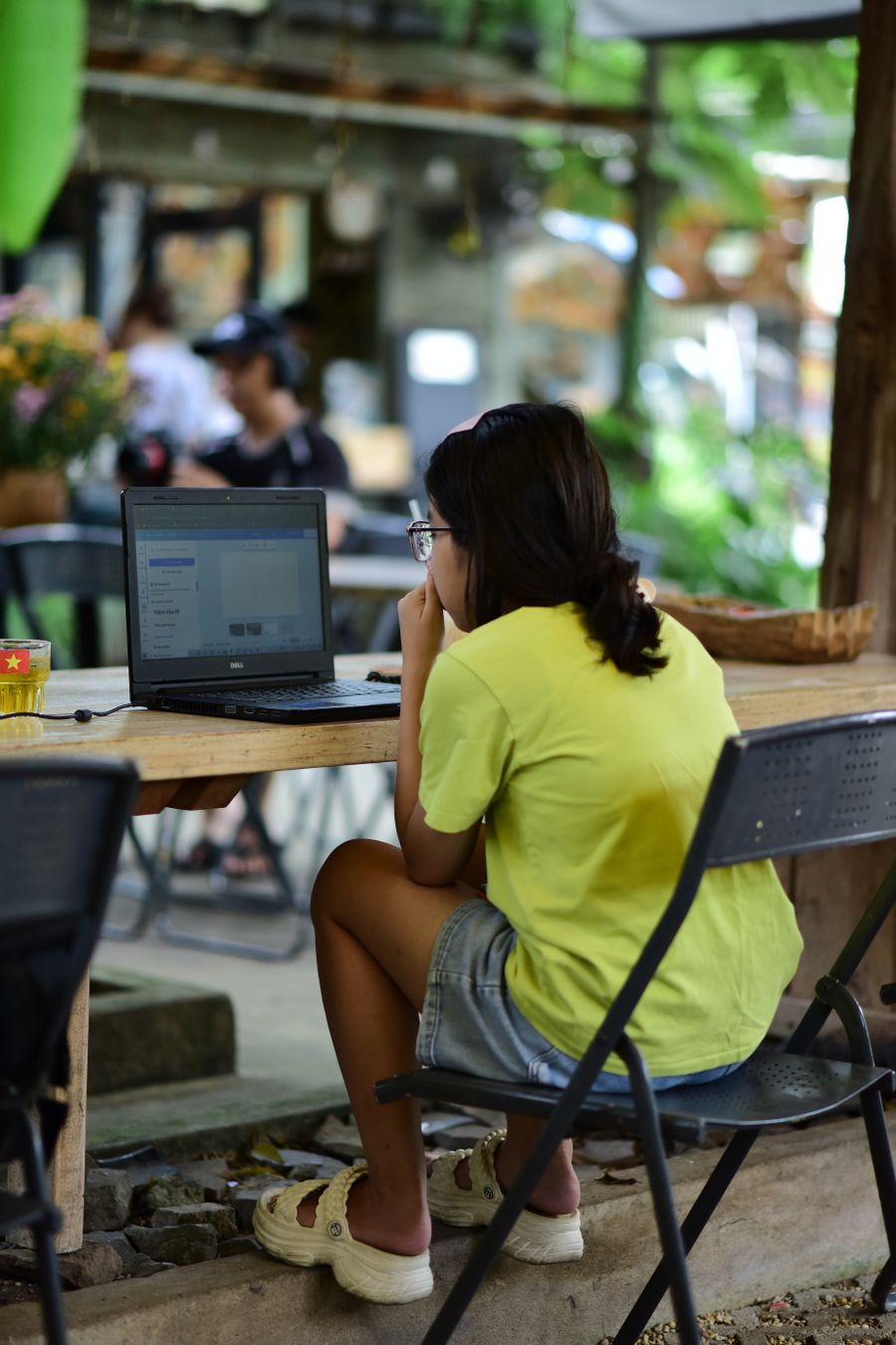 woman working on laptop in outdoor cafe setting — Island time, online time: ferries, beaches and full signal.