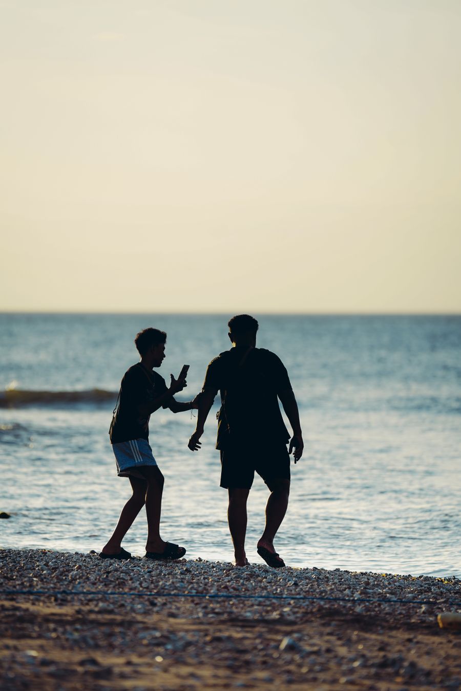 silhouette of two friends enjoying a beach sunset — El ferry del amanecer: boletos en la billetera, horario guardado offline.