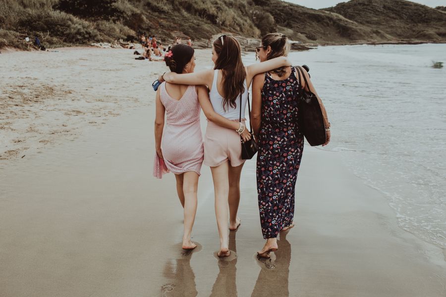 cheerful girlfriends walking together along sandy beach — From question to next step: Device Compatibility Checker shortens the path to a decision.