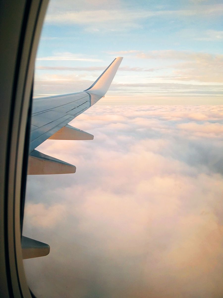wing of aircraft flying over clouds at sundown — Trenes nocturnos por Peru: boletos, horarios y taxis en una mano.