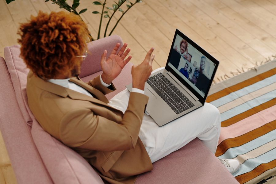 man sitting on sofa talking on webcam on laptop — Duty-free browsing: price-checked against home before buying.
