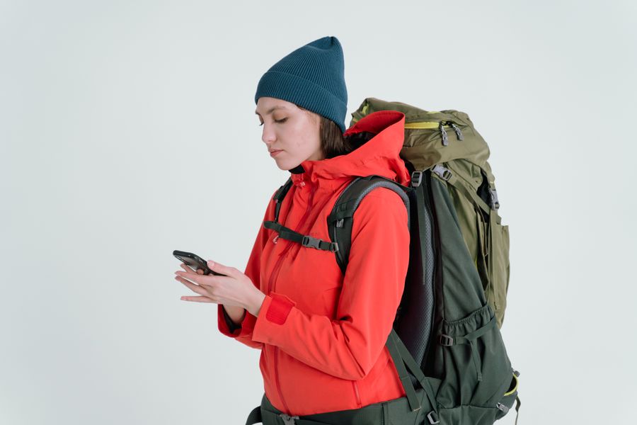 A woman in outdoor gear checking her smartphone, ready for adventure. — Mercados de Uruguay: regatea con el conversor abierto, paga con un toque.