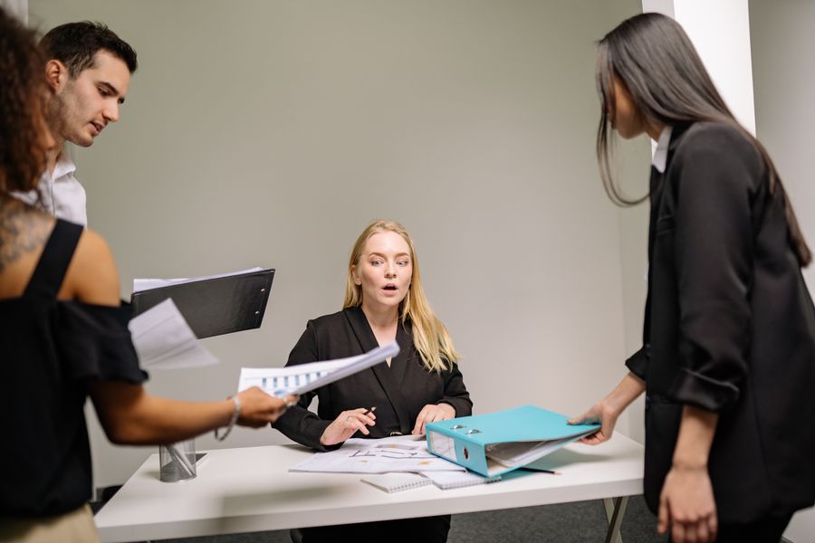 a woman in black blazer sitting at the desk with documents — Support: Viajes reales, conectividad real — para esto existe el producto.