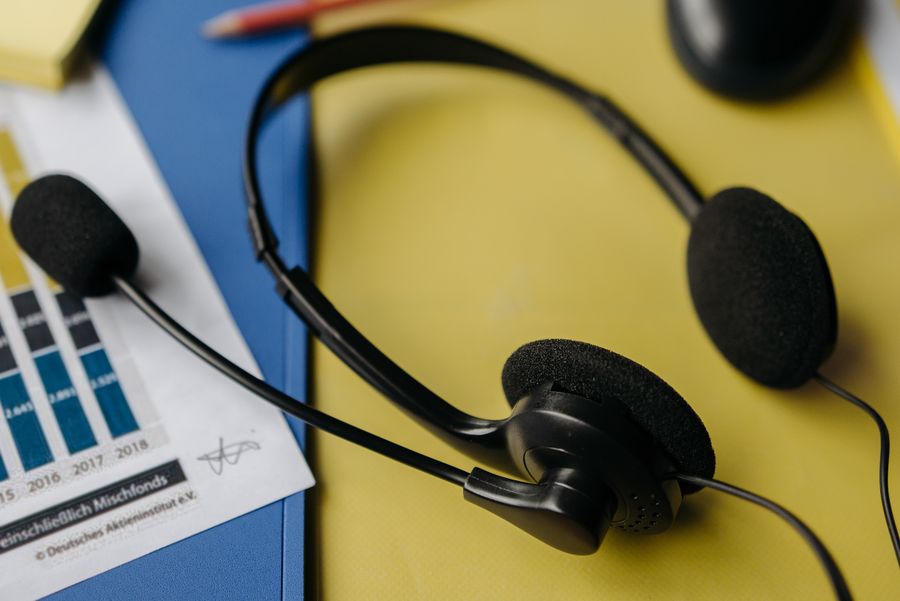 black headset on yellow file — Modo manos libres: el agente de voz te guía en la configuración mientras haces la maleta.