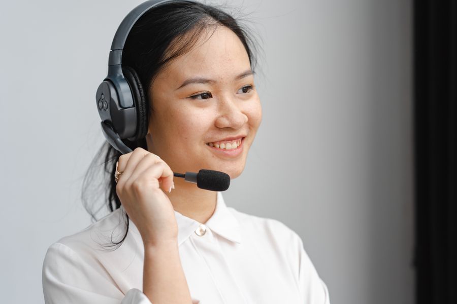 close up photo of a woman holding the microphone of her black headset — Docs: Plazas y paseos: videollamadas a casa con la vista detrás.