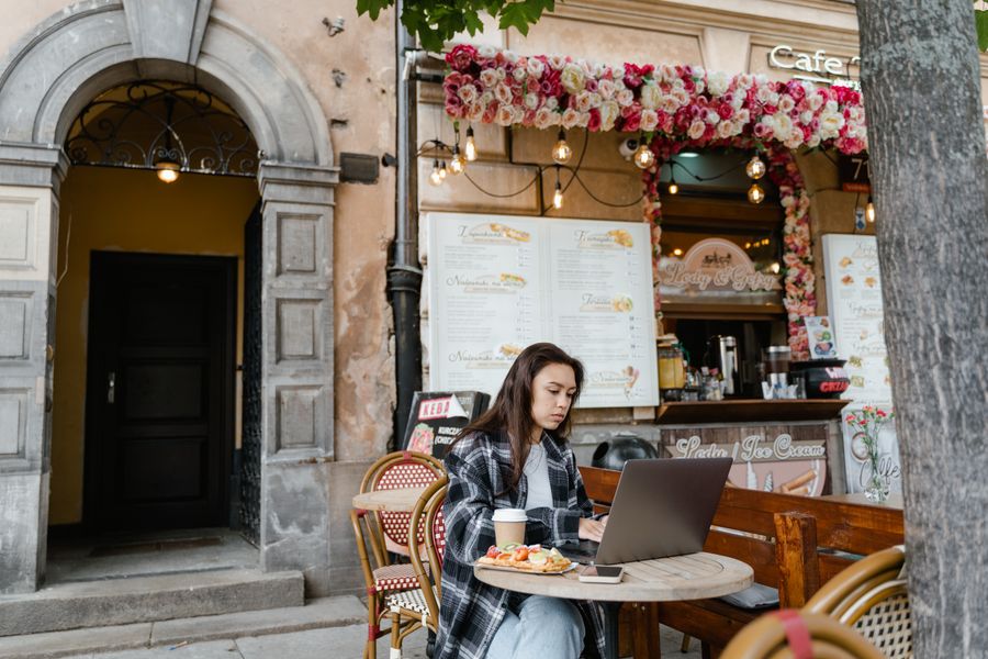 woman using laptop at a cafe — Developers: La credencial de la conferencia: boleto QR escaneado, agenda sincronizada.